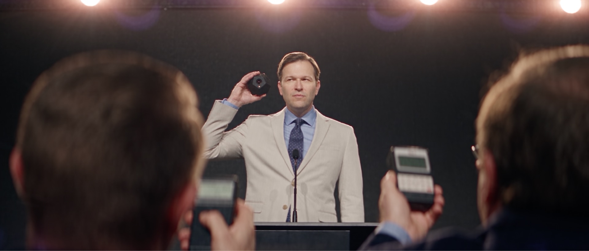 The Meridian CEO at a podium, holding the cube up
